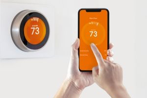 image of someone using a smartphone to adjust a smart thermostat